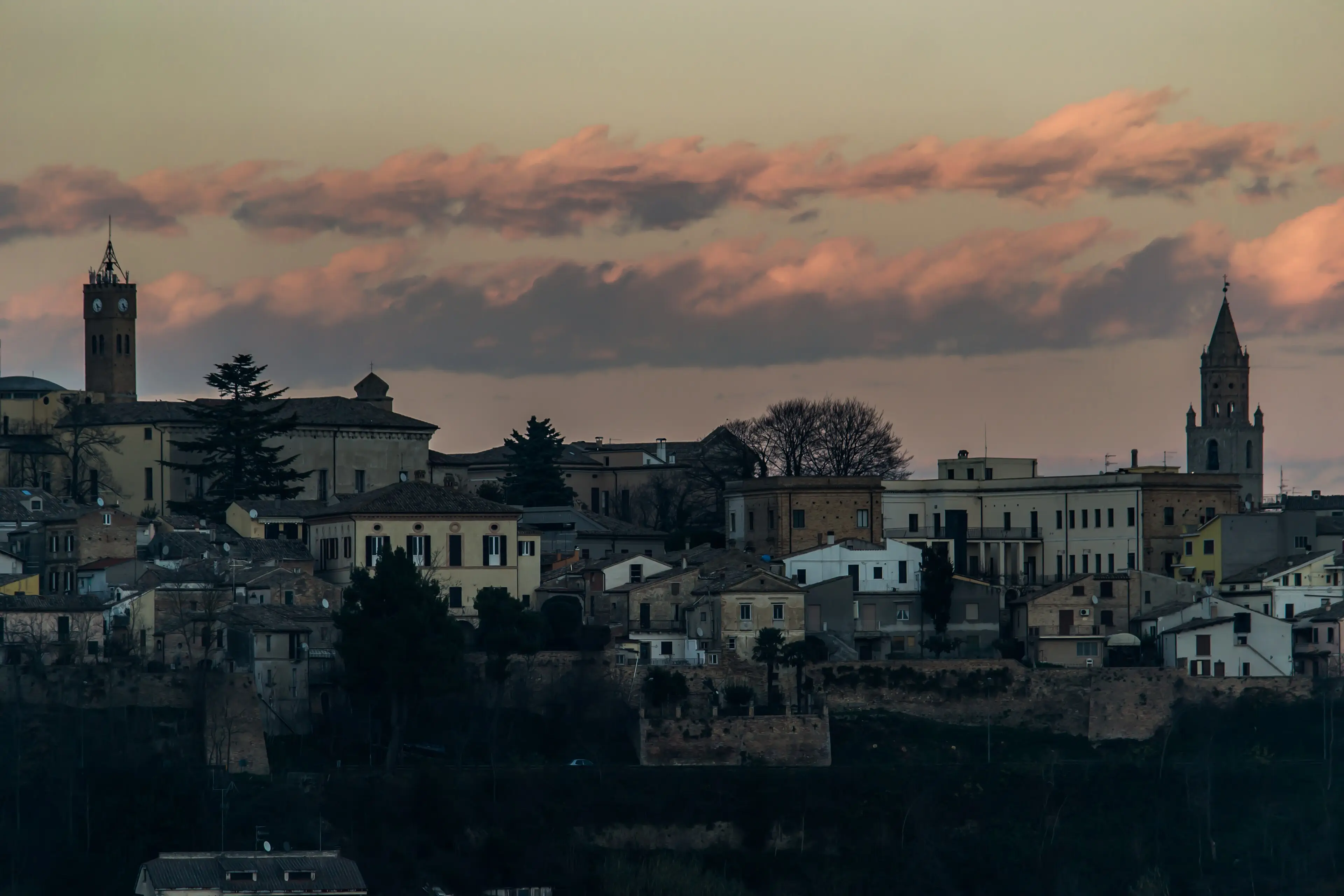 Il profilo di Atri al tramonto, con le nuvole accese di rosa sopra i tetti.
