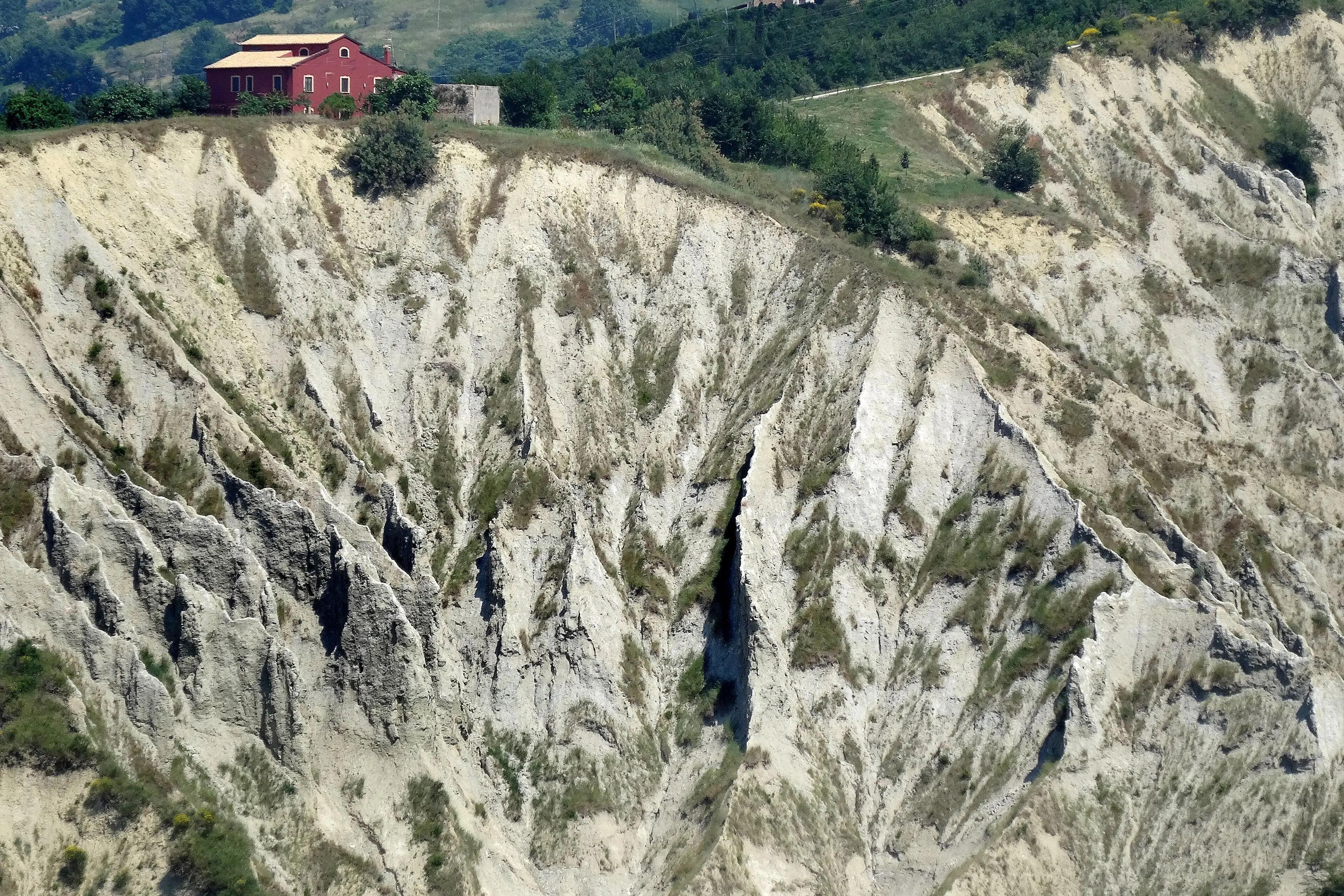 Una casa colonica rossa in bilico sul bordo dei calanchi di Atri.