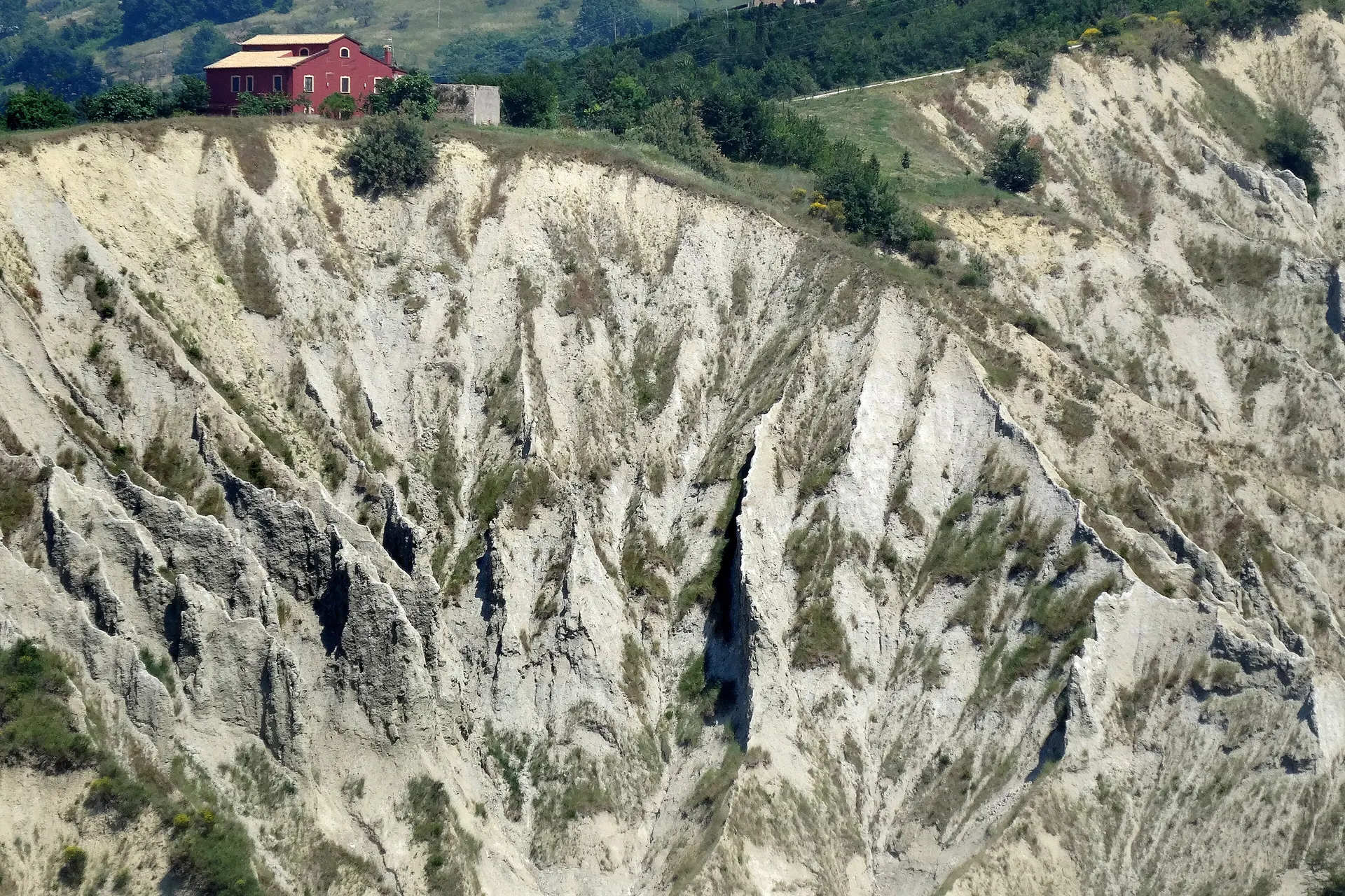 Una casa colonica rossa in bilico sul bordo dei calanchi di Atri.
